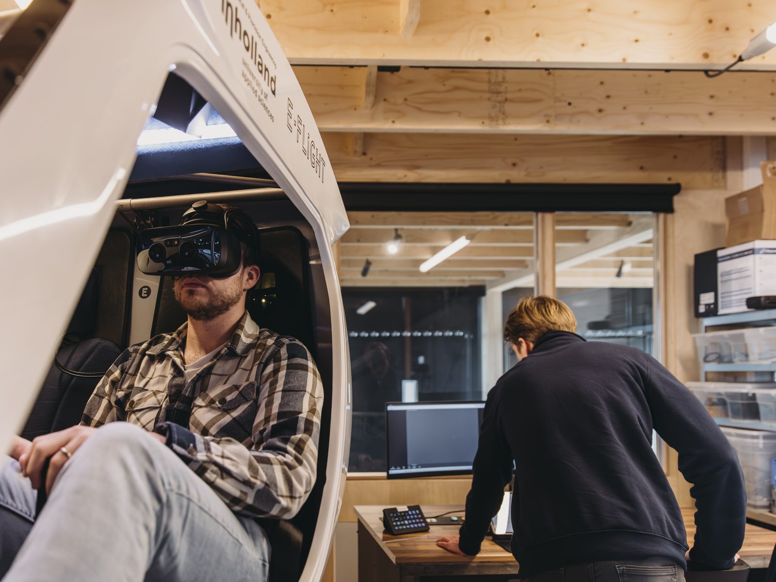 A pilot flying the VR Velis Simulator while an engineer watches from the operator desk